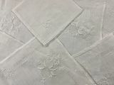 plusieurs serviettes de table en lin blanc ornées de fleurs brodées, posées sur une table