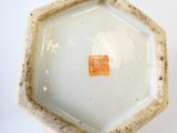 un petit vase blanc sur lequel est collé un autocollant orange