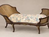 une chaise longue de style ancien avec un coussin rembourré à motifs floraux
