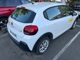 une voiture blanche garée sur un parking, avec d'autres voitures en arrière-plan