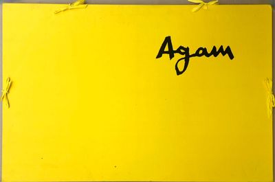 un gros plan d'un panneau jaune sur lequel figure le mot « agam »