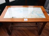une table en verre sur laquelle est posée une carte, posée sur un parquet