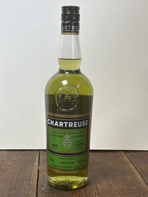 La bouteille de Chartreuse est posée sur une table en bois.