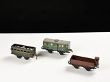trois petits trains miniatures posés sur une surface blanche, sur fond noir