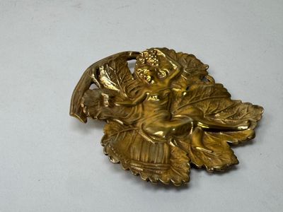 une broche en or représentant une femme tenant un panier de raisins