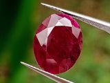 un gros plan d'un diamant rouge tenu par une pince