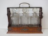 an old fashioned glass decanter with four bottles on a wooden stand