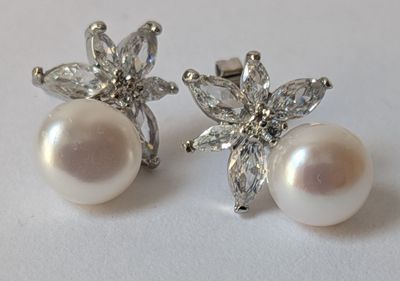 pair of pearl and diamond earrings on a white surface