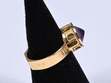 an image of a gold ring with a purple stone on it