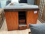 un lit avec une tête de lit en bois et des tiroirs dans une chambre