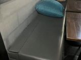 un banc sur lequel est posé un coussin, à côté d'une table