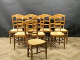 a set of six chairs with wooden seats in a room