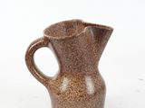 a small brown pitcher sitting on a white surface