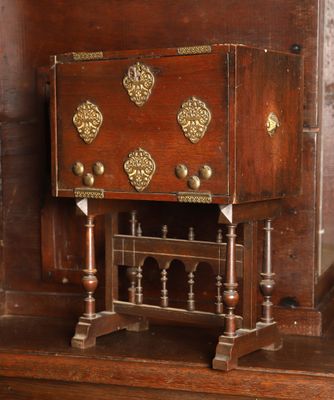 une petite armoire en bois ornée de décorations en laiton sur le dessus