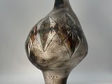 a black and silver vase sitting on a white surface