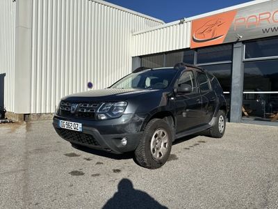 une voiture noire garée devant un immeuble sur lequel est accrochée une pancarte