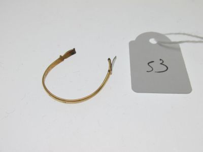 une paire de boucles d'oreilles en or en forme d'anneau, avec son étiquette de prix, posée sur une table blanche