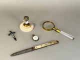 a knife, a watch, a magnifying glass, and a pocket watch on a table