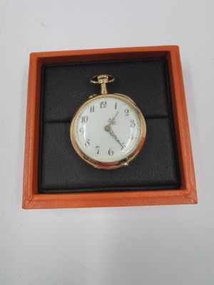 une montre de poche en or dans un écrin posé sur une surface blanche