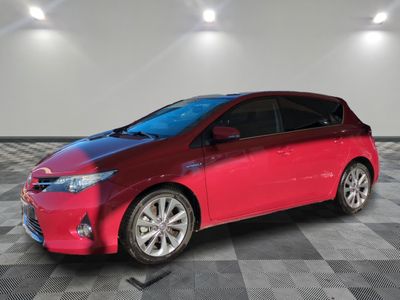 La Toyota Prius rouge est garée sur un sol en carrelage à damier.