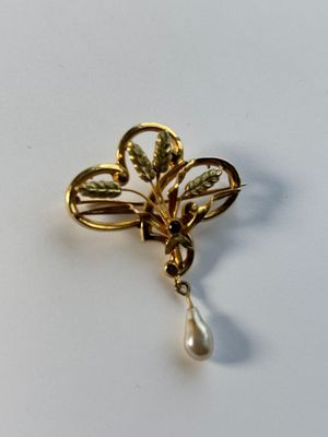 une broche en or à laquelle est suspendue une perle