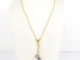 a gold necklace with a black pearl on a mannequin neck