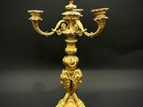 un chandelier ancien en laiton à trois bougies, posé sur un socle