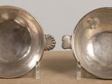 pair of silver plated bowls with handles on stand on table