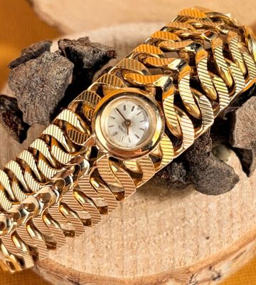 a gold bracelet with a watch on top of it