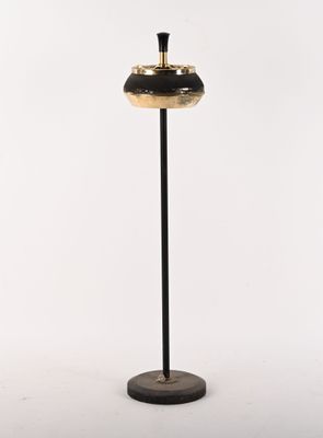 une lampe noire et dorée posée sur un pied noir, sur fond blanc