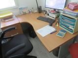 a desk with a computer, keyboard, and a calculator on it