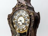 a clock that is sitting on a stand on a white surface