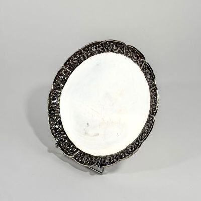 une image représentant une assiette en argent posée sur un support, sur fond blanc