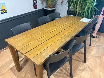 une table en bois avec des chaises et une plante dans un coin