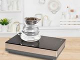 une cafetière en verre posée sur une table en bois