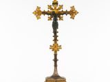 a gold and black cross on a stand with a cross on top