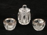 three pieces of glass on a black surface with a silver lid