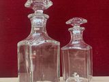 two glass bottles sitting on a table with a red background