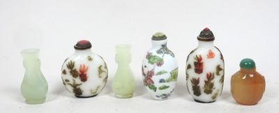 cinq vases en verre posés les uns à côté des autres sur une surface blanche
