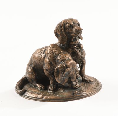 statue représentant deux chiens assis sur une assiette posée sur une surface blanche