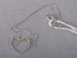 un collier en argent orné d'un cœur et d'un oiseau