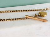collier plaqué or composé d'une chaîne en or et d'un stylo posé sur une surface en marbre