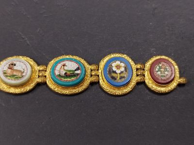 a close up of a gold bracelet with four different colored buttons