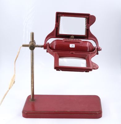 un petit objet rouge posé sur un socle, muni d'une loupe