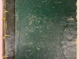 un vieux livre à la couverture verte posé sur une table