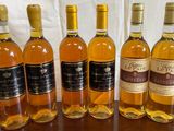 six bouteilles de vin sont alignées sur une table en bois
