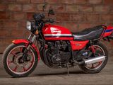 a red and black motorcycle parked in front of a brick wall