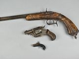 an old gun with a wooden handle and two smaller revolvers