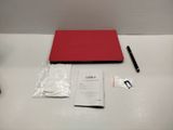 a red laptop sitting on a table with a pen next to it