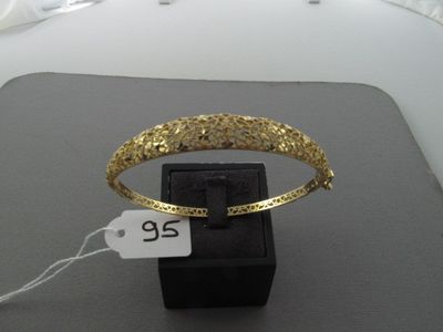 un bracelet en or muni d'une étiquette de prix, posé sur une boîte noire